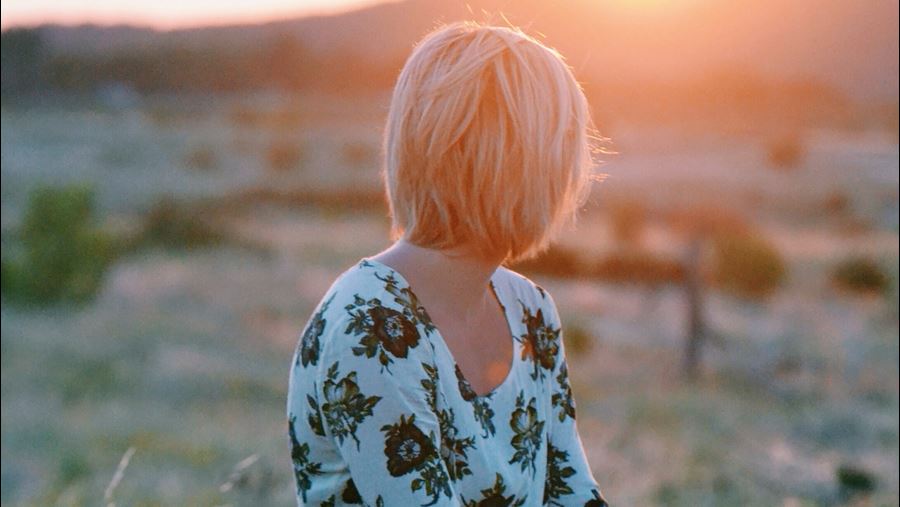 Vrouw kijkt naar ondergaande zon achter berg Vrouw kijkt naar ondergaande zon achter berg